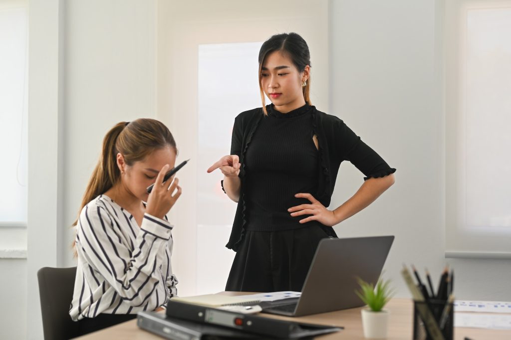 Furious asian female manager scolding frustrated interns.