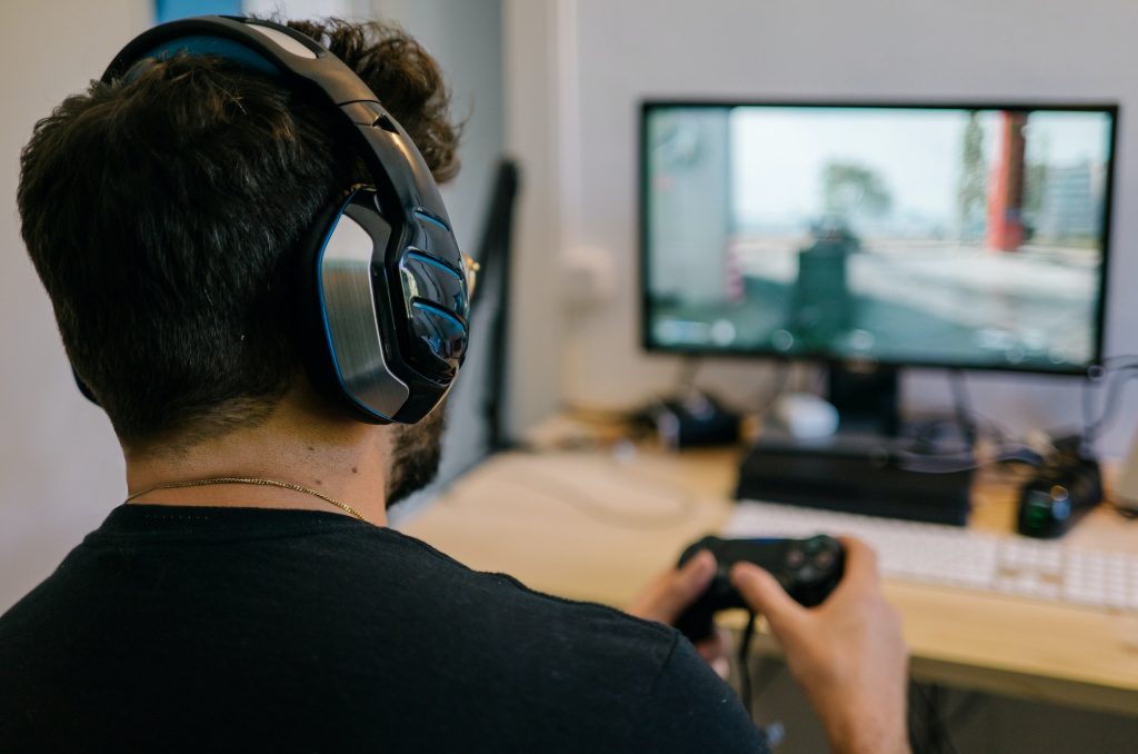 Young man having fun playing video games online using headphones