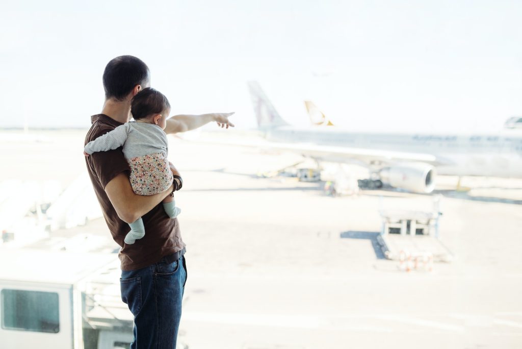 Spain, Barcelona, Man holding a baby girl at the airport pointing at the airplanes
