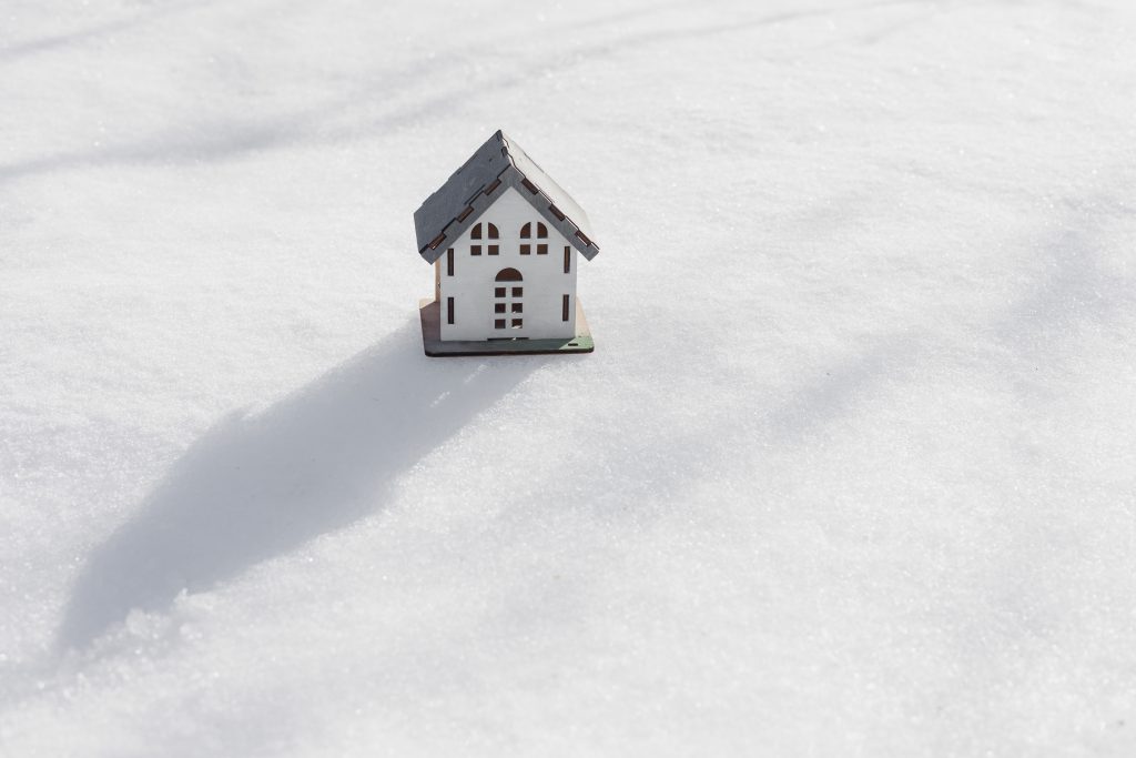 model of house is standing in snow, mock-up, sale of real estate, rent of an apartment or house.