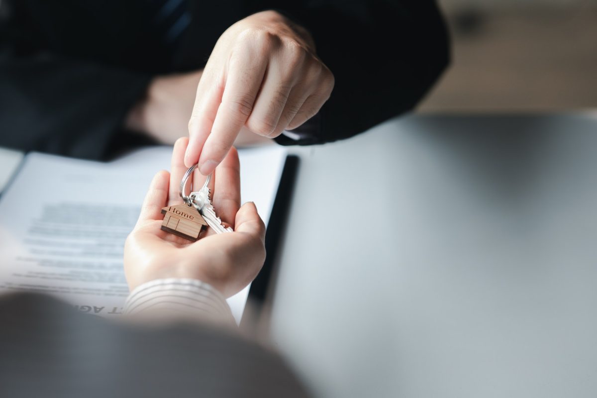 A home rental company employee is handing the house keys.