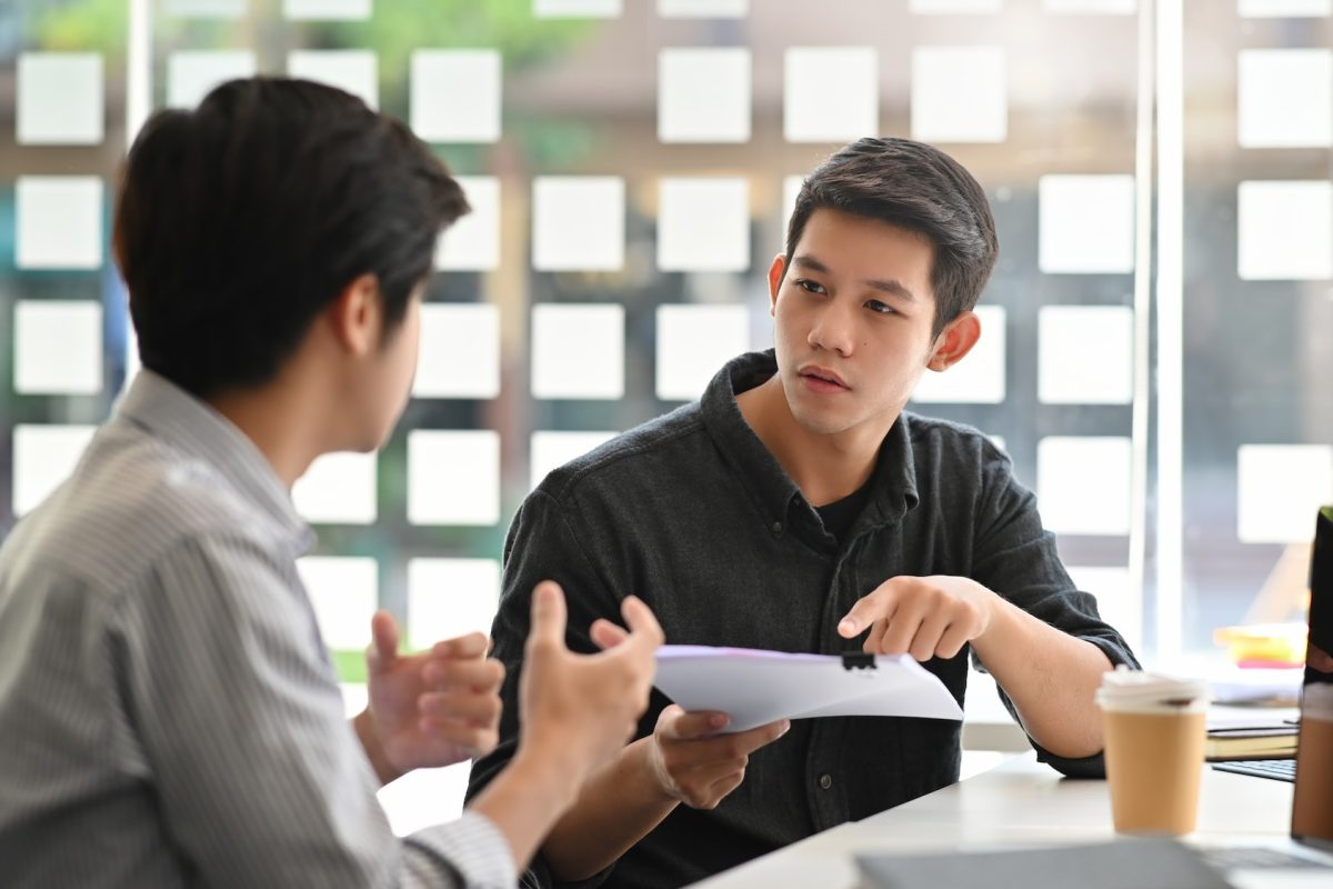 Asian young man consulting with paper document on modern office.