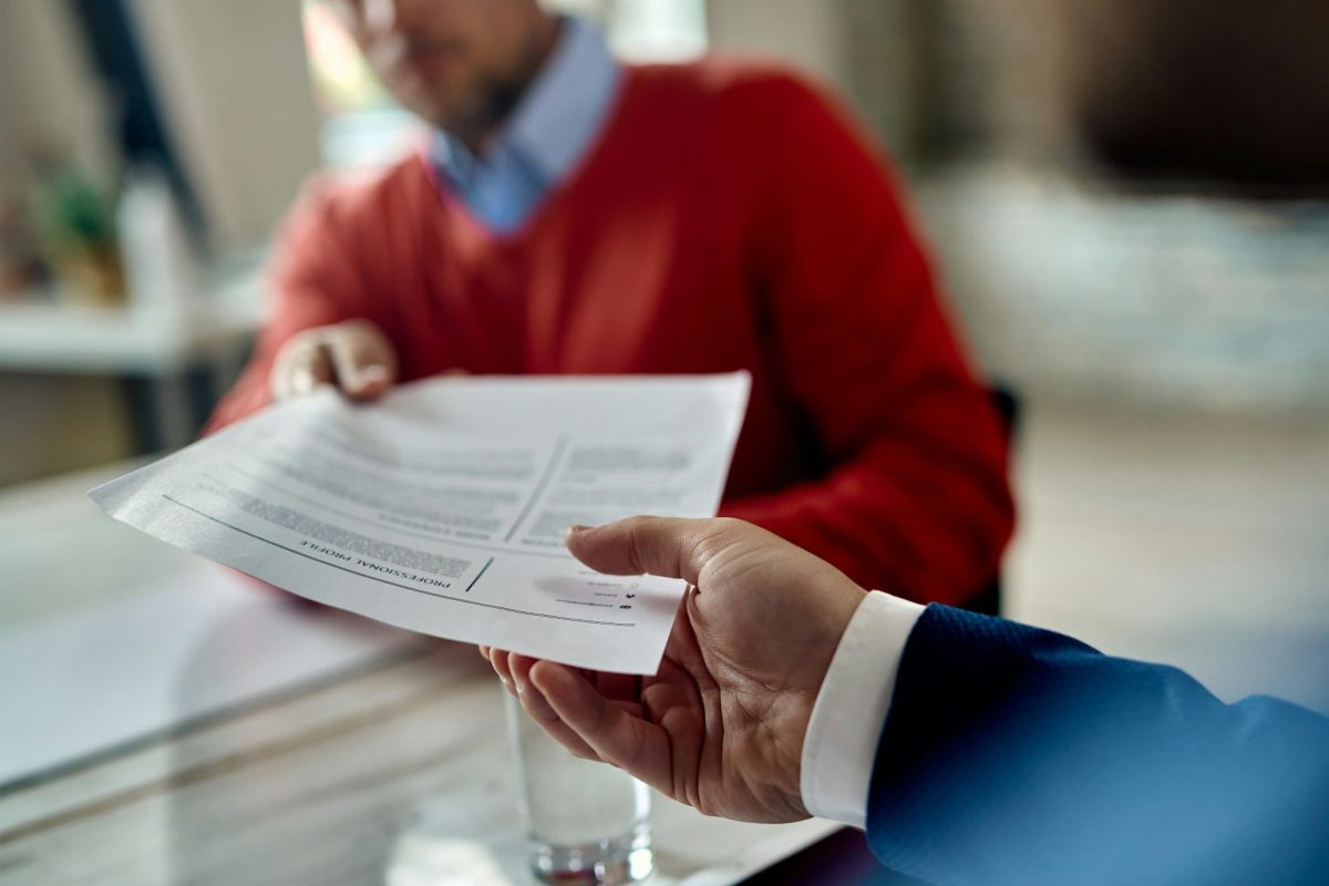 Close-up of job applicant giving his resume during job interview.