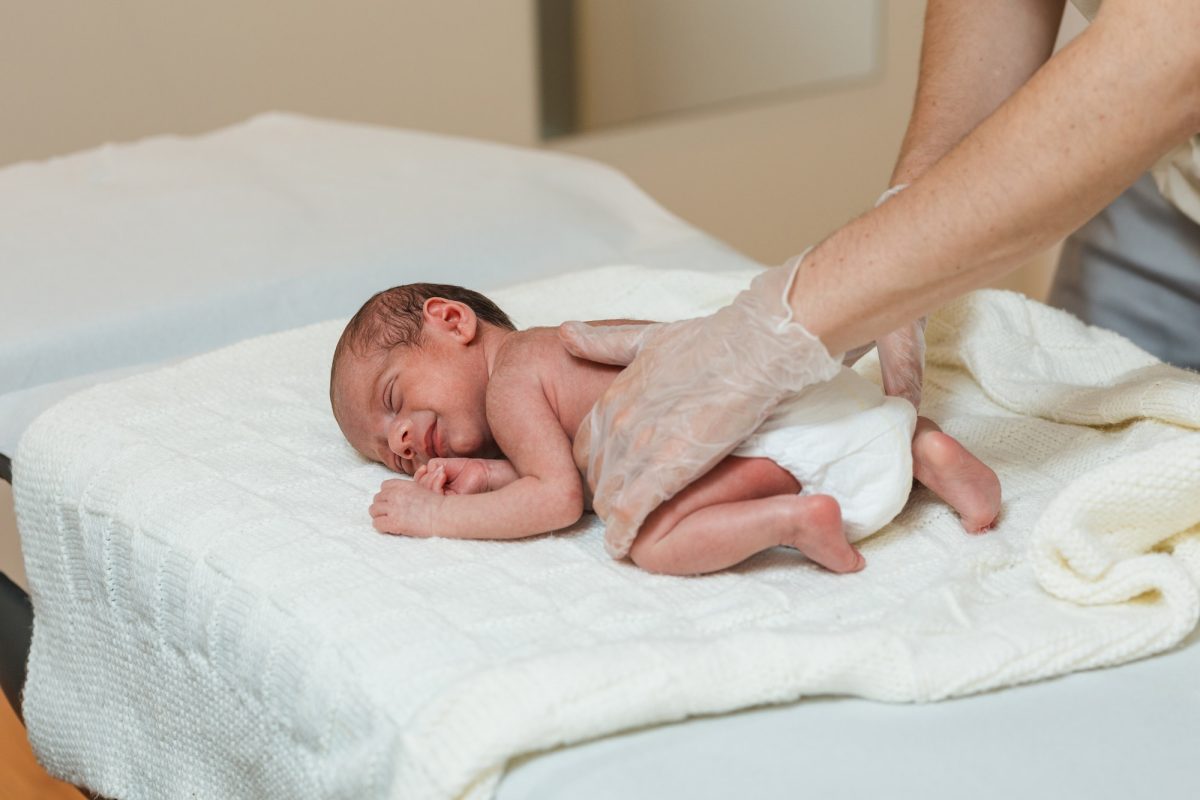 Physiotherapist performing an evaluation on the spine of a newborn baby