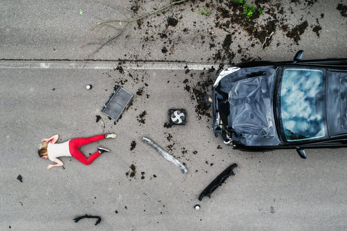 Young injured woman lying on the road after a car accident, unconscious.